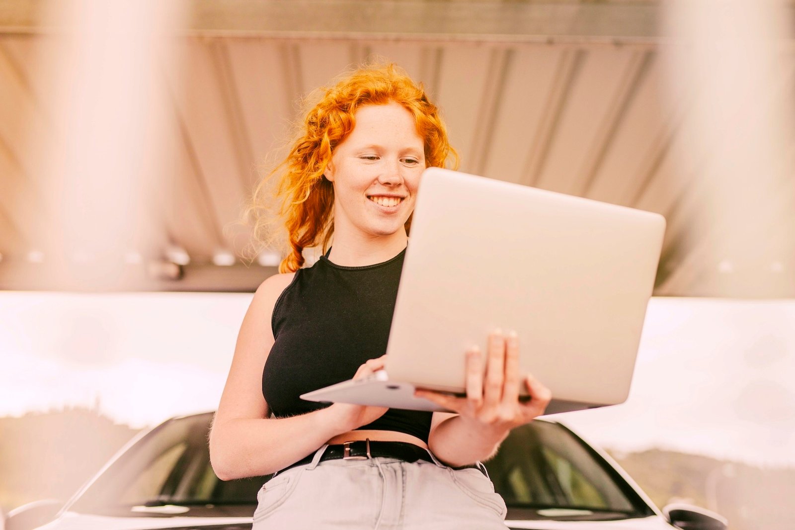 Smiling red-haired woman holding a laptop, looking approachable and friendly